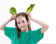 Kind hält Salatblätter wie Ohren